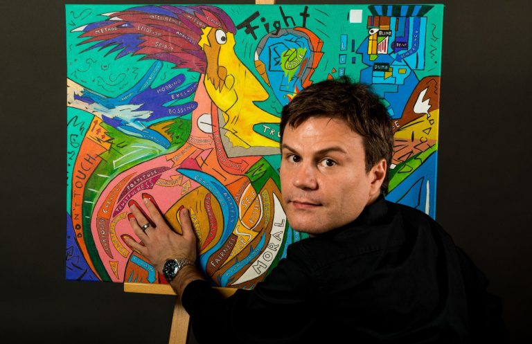 Der Künstler blickt in die Kamera und legt seine Hand auf ein expressives, buntes Kunstwerk.