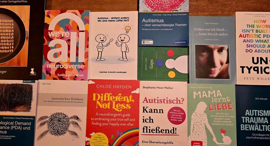 Auswahl von deutschen und englischen Fachbüchern zu Autismus auf einem Holztisch angeordnet.